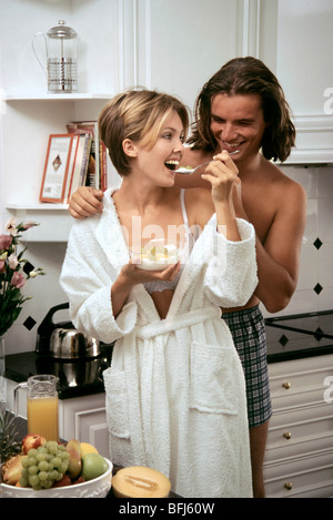 Young couple sharing healthy fruit breakfast in modern kitchen. Stock Photo