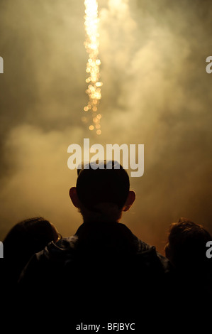 rear view of three people watching a November 5th Guy Fawkes night fireworks display, Llanilar village Wales UK Stock Photo
