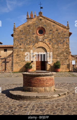 The Romanesque  church of  Santa Maria Assunta Church with a well in front in Piazza Roma, in Monteriggioni , Tuscany Italy Stock Photo