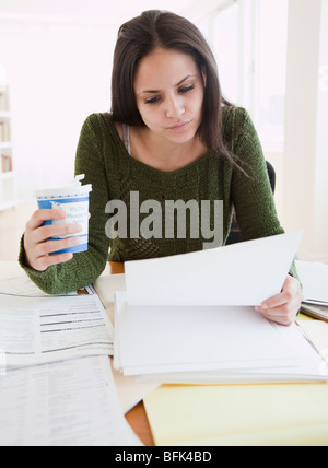 Mixed race woman working and drinking coffee Stock Photo