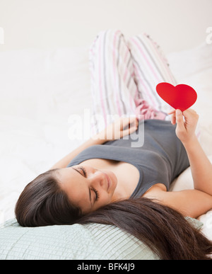 Mixed race woman holding red paper heart Stock Photo