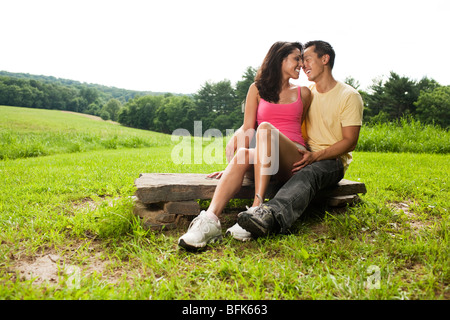 Hispanic woman sitting on rock in field