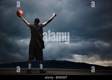 Mixed race basketball player standing with storm clouds in distance Stock Photo