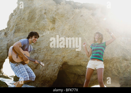 Man playing guitar for girlfriend on beach Stock Photo