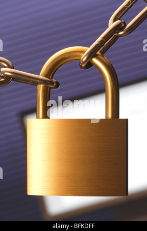 Chain and padlock with computer monitor in background close up Stock Photo