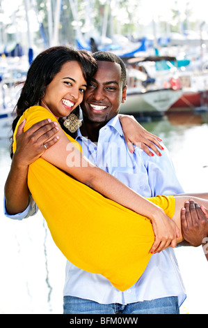 Man carrying his girlfriend standing at harbor Stock Photo