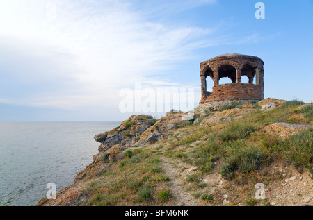 Rocky summer coastline and cape with pavilion on blue sky background Stock Photo