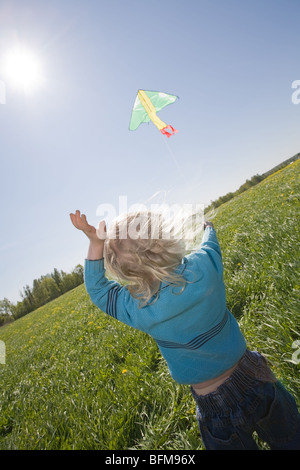 young girl flying kite on a green meadow Stock Photo