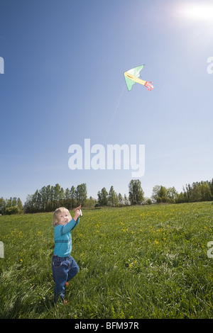 young girl flying kite on a green meadow Stock Photo