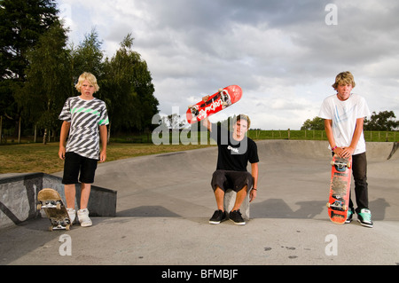 3 boys doing tricks in skate park with setting sun, Cambridge, New Zealand, Stock Photo