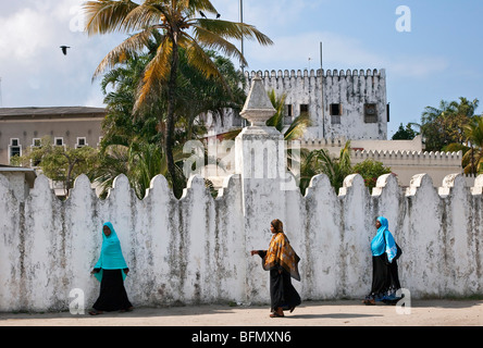 Tanzania, Zanzibar, Stone Town. Zanzibari women walk along Mzingani Road past the Palace Museum in Zanzibar  s Stone Town. Stock Photo