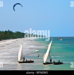 Kenya, Mombasa. A kite surfer and outrigger canoes beach at Diani Beach, a popular tourist destination on Kenya s south coast. Stock Photo