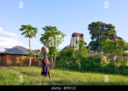 Kenya, Nyanza District.  A Luo woman carries a large water pot to her home near Kit Mikayi Stock Photo