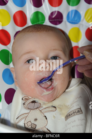 Four month old baby boy being spoon fed with his first solid food uk Stock Photo