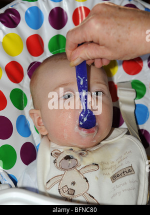 Four month old baby boy being spoon fed with his first solid food uk Stock Photo