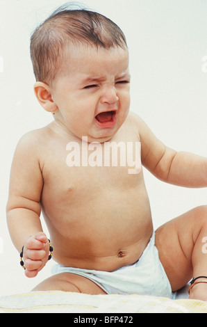 Indian baby girl crying ; wearing nappy diaper and amulet ; white background  ; india ; asia ; MR#191 Stock Photo