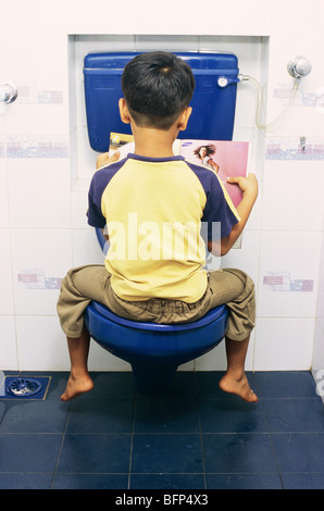 RMM 63779 : Boy in toilet sitting on commode reading book MR#152 Stock Photo