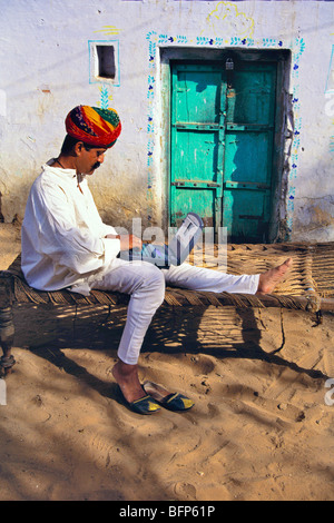 Rajasthani rajput man using laptop outside his house ; Pushkar ; Rajasthan ; India MR#672 Stock Photo