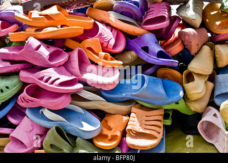 A stack of colorful plastic sandals for sale in a market Stock Photo