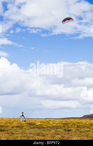 Two brothers struggling to fly a power kite in high winds on moorland east of Syre, Sutherland, Highland, Scotland Stock Photo