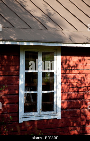 Window in red ochre painted log cabin timber wall , Finland Stock Photo