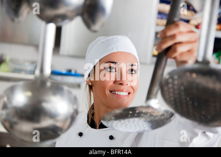 mid adult female chef taking kitchen utensil Stock Photo