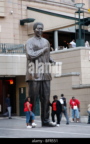 Tourists posing next to a statue of Nelson Mandela in Mandela Square in Sandton Stock Photo