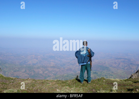 A local guide with a rifle over his shoulder looking over the hills and valleys below in the Simien Mountains Stock Photo