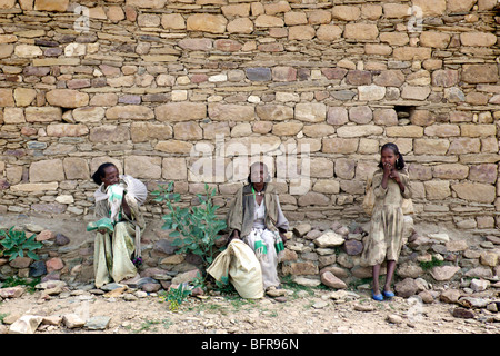 Three local women carrying bags on their backs resting in the shade outside a Coptic church Stock Photo