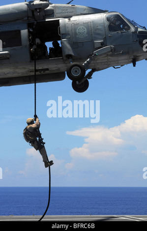 An explosive ordnance disposal technician fast ropes onto the flight deck of the USS Ronald Reagan. Stock Photo