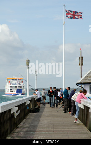 Yarmouth Pier Isle of Wight southern England visitors and fishermen on the wooden decking which is inscribed with names Stock Photo