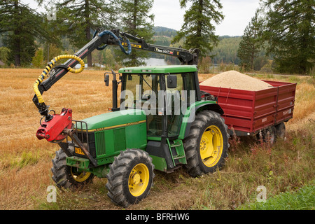 Green John Deere tractor with red trailer loaded with harvested grain , Finland Stock Photo