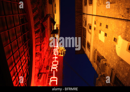 A neon sign for a trattoria contrasts with old bulidings in Florence, Italy. Stock Photo