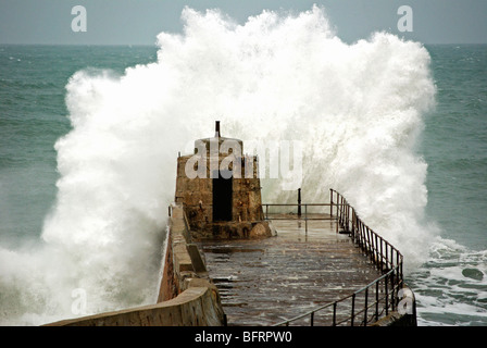 waves breaking over the old pier at portreath in cornwall, uk Stock Photo