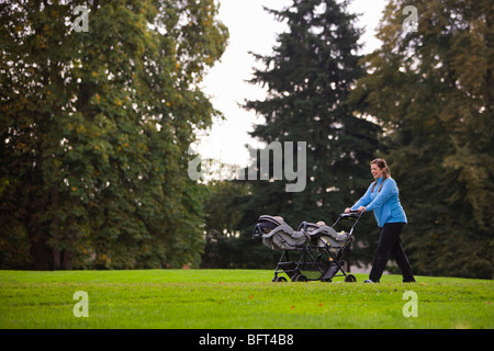 Woman Pushing Stroller in Park Stock Photo