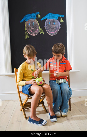 Boy and Girl putting Money in Piggy Bank for College Fund Stock Photo