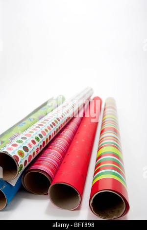 Rolls of colored wrapping paper with scissors and gift on white