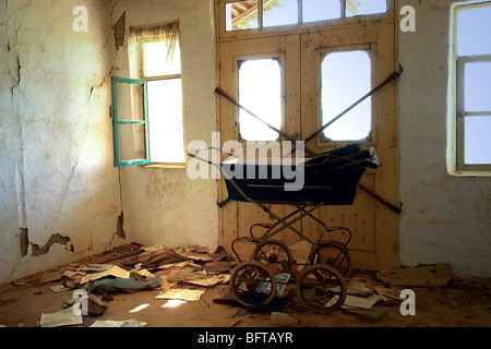 Room of abandoned house with baby carriage and notepads on the floor. Stock Photo