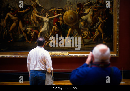 Tourists viewing the painting The Intervention of the Sabine Women by Jacques-Louis David in the Louvre Museum Paris France Stock Photo