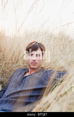 man lying in reed looking at viewer Stock Photo