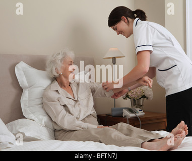 Nurse rolling up elderly woman's sleeve Stock Photo