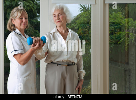 Nurse helping woman with exercises Stock Photo