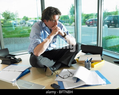 Man sitting on his desk, thinking Stock Photo