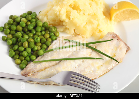 Baked fish fillets served with boiled peas and mashed potatoes and garnished with chives. Stock Photo