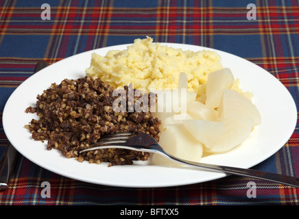A Burns Night supper of haggis, tatties and neeps on a tartan background Stock Photo