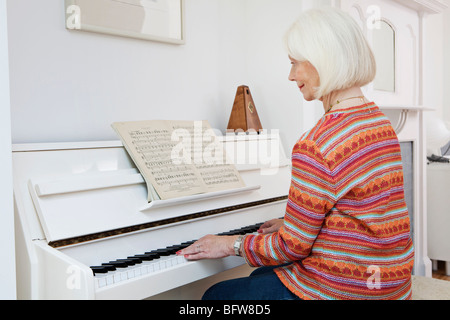 A senior female playing the piano Stock Photo