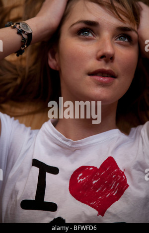 woman lying down holding head, with I love on her shirt Stock Photo