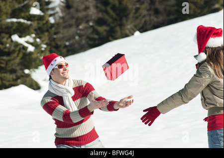 Couple in Christmas outfit, throwing a present Stock Photo