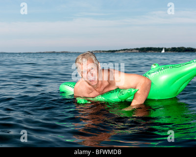 Senior man on inflatable crocodile