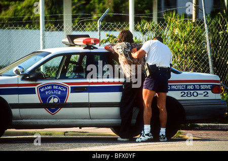 A Miami Beach police officer searches a suspect in Miami, Florida Stock Photo